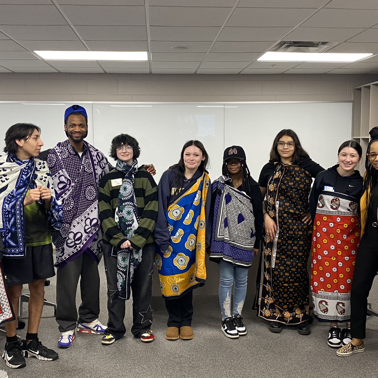 high school students posing for a group picture after looking about kanga cloth from Swahili faculty