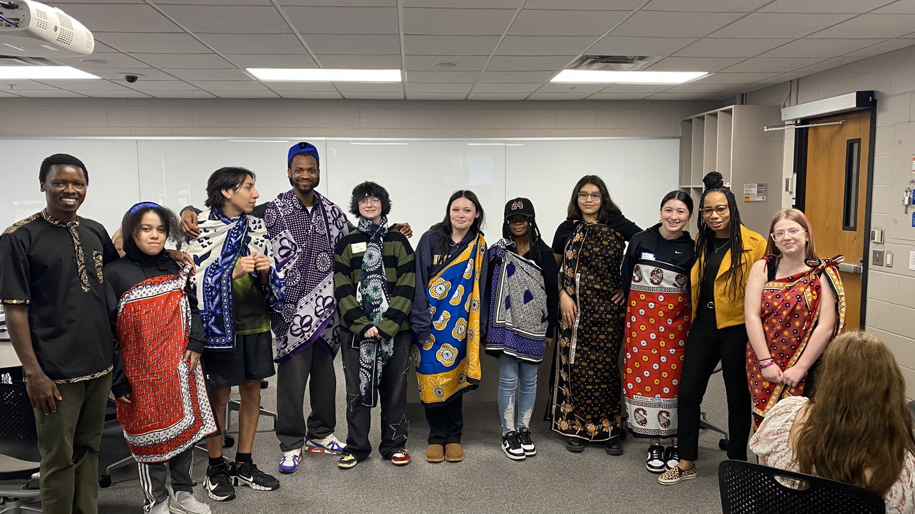 high school students posing for a group picture after looking about kanga cloth from Swahili faculty