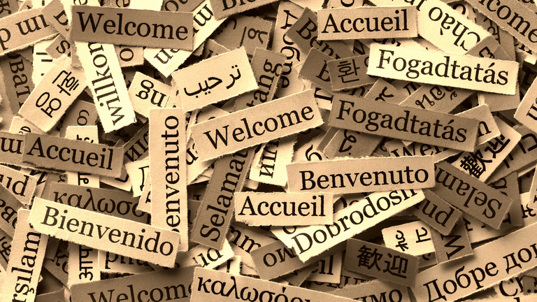 The word Welcome written on document paper in various world languages.